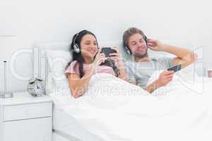 Couple listening to music in their bed with smartphones