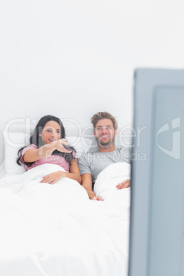 Woman changing channel in her bed