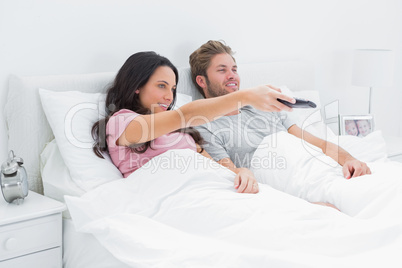Woman changing tv channel in her bed