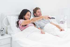 Woman changing tv channel in her bed