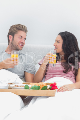 Cheerful couple having breakfast in bed