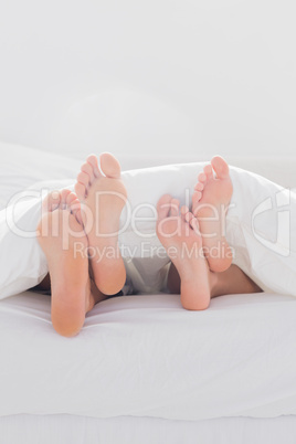 Couple crossing their feet under the duvet