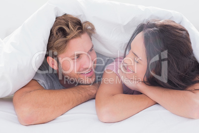 Couple under quilt smiling