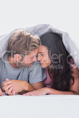 Couple under quilt hand in hand