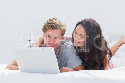 Woman embracing husband while using a laptop