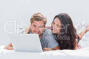 Woman embracing husband while using a laptop