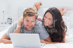 Attractive woman embracing husband while using a laptop