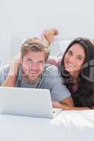 Happy woman embracing husband while using a laptop