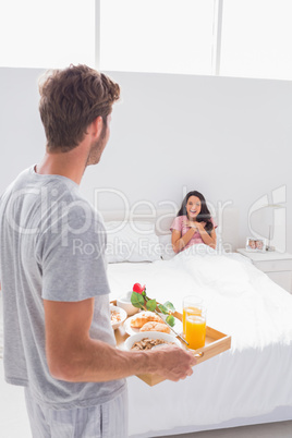 Man bringing breakfast to his surprised wife