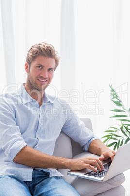 Attractive man sitting on the couch and using his laptop