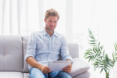 Man using a tablet while he is sat on the couch