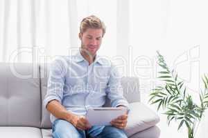 Man using a tablet while he is sat on the couch