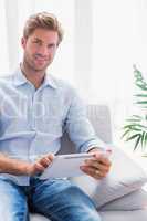 Handsome man using a tablet pc on his couch