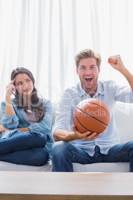Woman looking at her husband cheering the basketball game