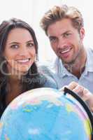 Portrait of a beautiful couple looking at a globe