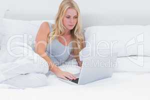 Woman lying on her bed using a laptop