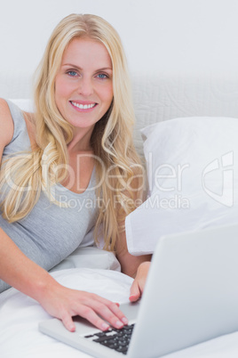 Woman using her laptop on her bed