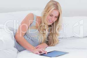 Woman in her bed touching her tablet