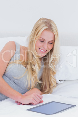 Woman in her bed touching a tablet pc