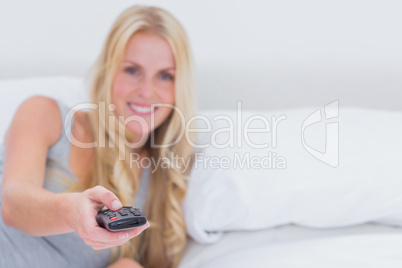 Woman pointing the remote control at the camera
