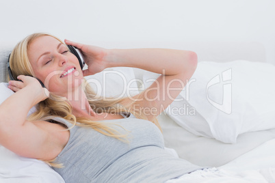 Woman listening to music while she is laid in her bed