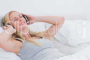 Woman listening to music while she is laid in her bed
