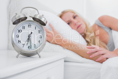 Tired woman looking at the alarm clock