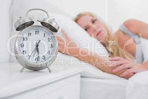 Tired woman looking at the alarm clock