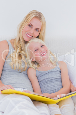 Mother holding a story book with her daughter