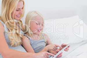 Cheerful mother and daughter using a tablet