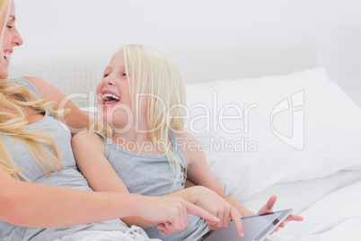 Mother and daughter laughing while using a tablet