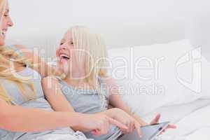 Mother and daughter laughing while using a tablet
