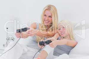 Cheerful mother and daughter playing video games