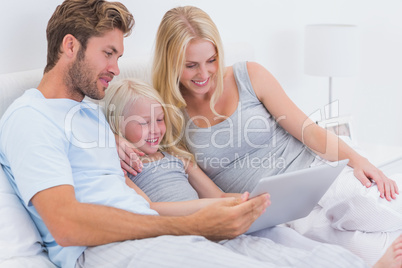 Couple using a laptop with their daughter Couple using a laptop with their daughter