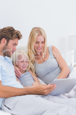 Beautiful couple using a laptop with their daughter