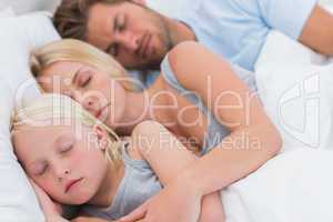 Cute couple sleeping with daughter