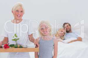 Children bringing breakfast in bed to their parents