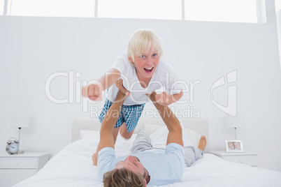 Father playing airplane holding his son