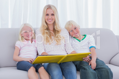 Portrait of a mother holding a story book with children