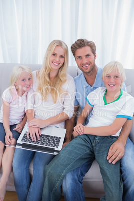 Smiling family using laptop in their living room