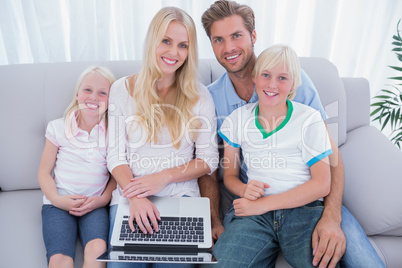 Cheerful family using laptop in the living room