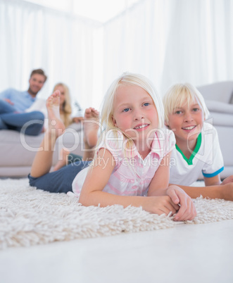 Cute children lying on the carpet smiling at camera