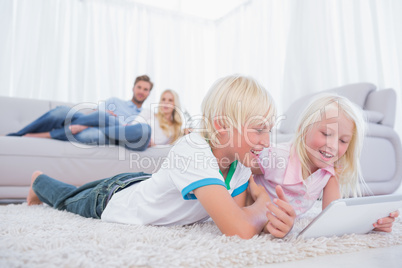 Children lying on the carpet using digital tablet