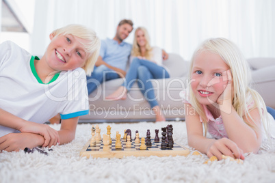 Children playing chess in front of their parents