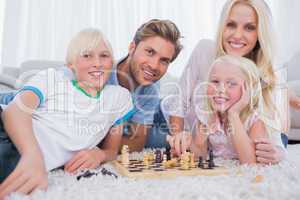 Smiling family playing chess together