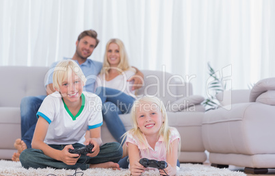 Children sitting on the carpet playing video games