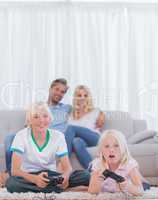 Children on the carpet playing video games while their parents a