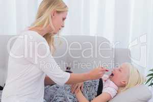 Mother giving her daughter medicine on a spoon
