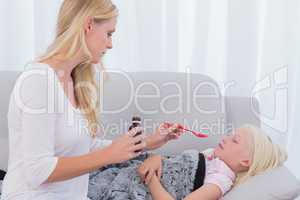 Concerned mother giving her daughter medicine