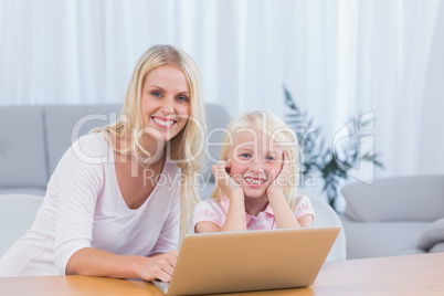 Smiling mother using laptop with her daughter